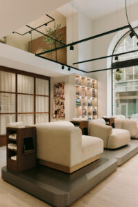 Lounge-Bereich mit Sitzmöbeln, Regalwand und Blick auf die Galerieebene